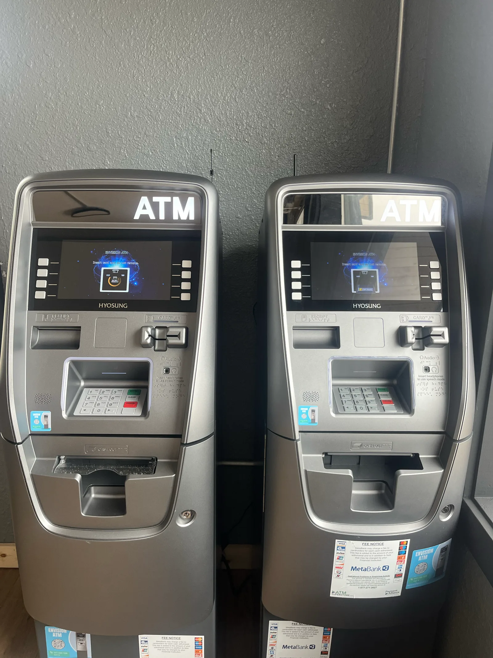 Two ATMs side by side showing network acceptance stickers